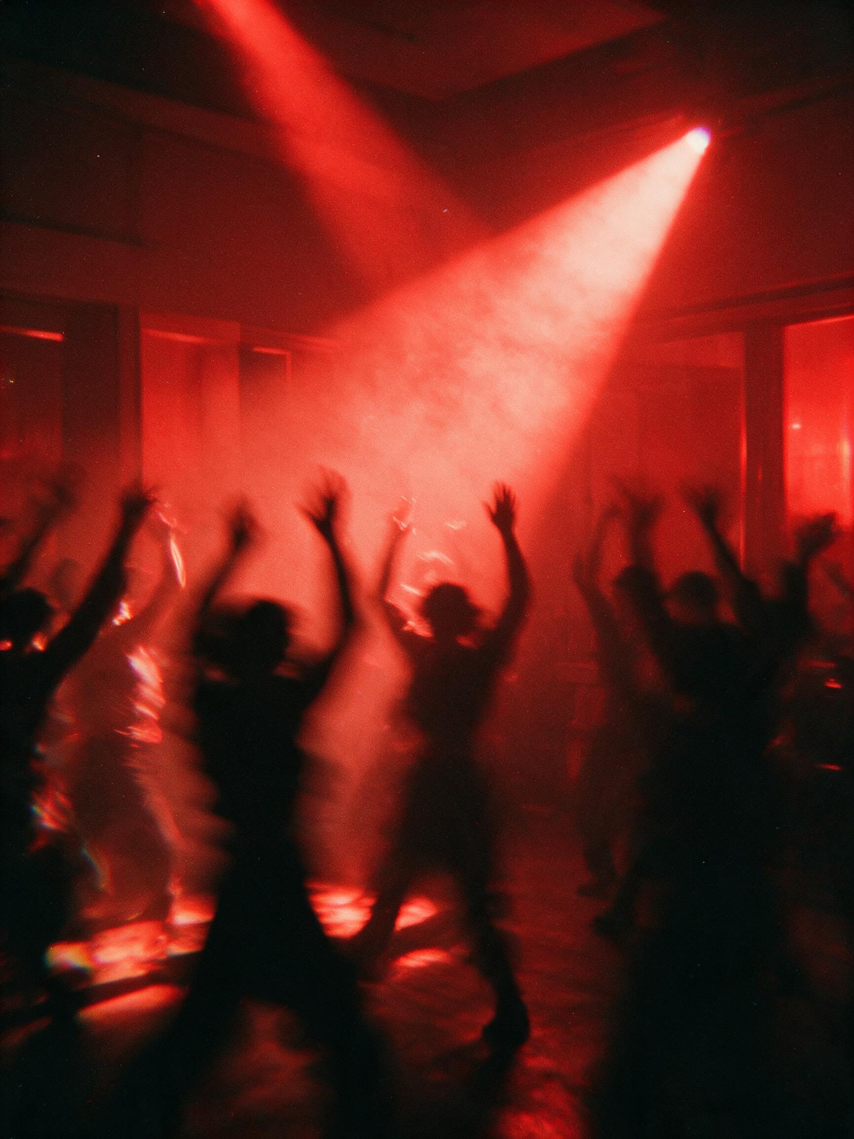 Silhouettes dancing under a beam of red light
